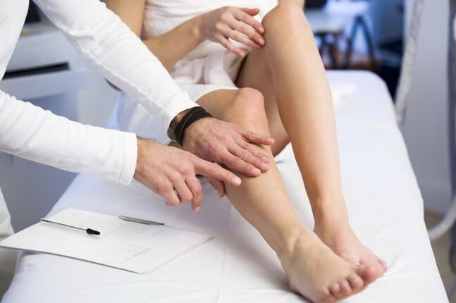 The doctor examines a leg with reticular varicose veins